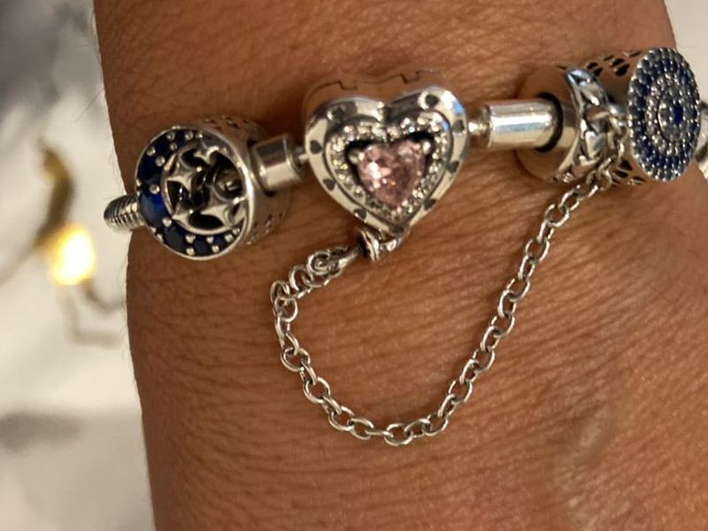 Detalle de la pulsera corazón rosado con cadena de seguridad en la muñeca